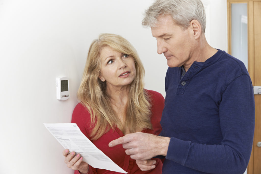 Worried Mature Couple With Bill Turning Down Central Heating