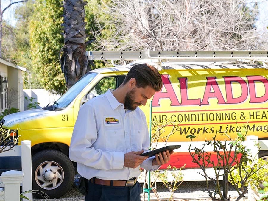 An Aladdin Air Conditioning & Heating technician in front of their service truck.